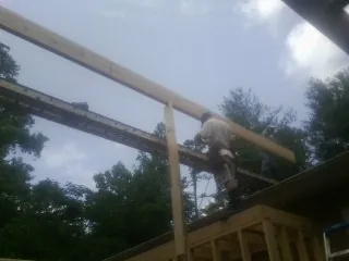 Carpenter setting a ridge beam over a new addition frame — Ice Dam Removal by Roofing Brothers in Central Square