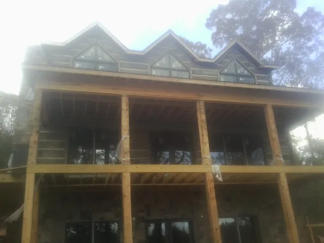 Dormers and porch framing on a large log home under construction — Roof Coating work by our crew in Central Square