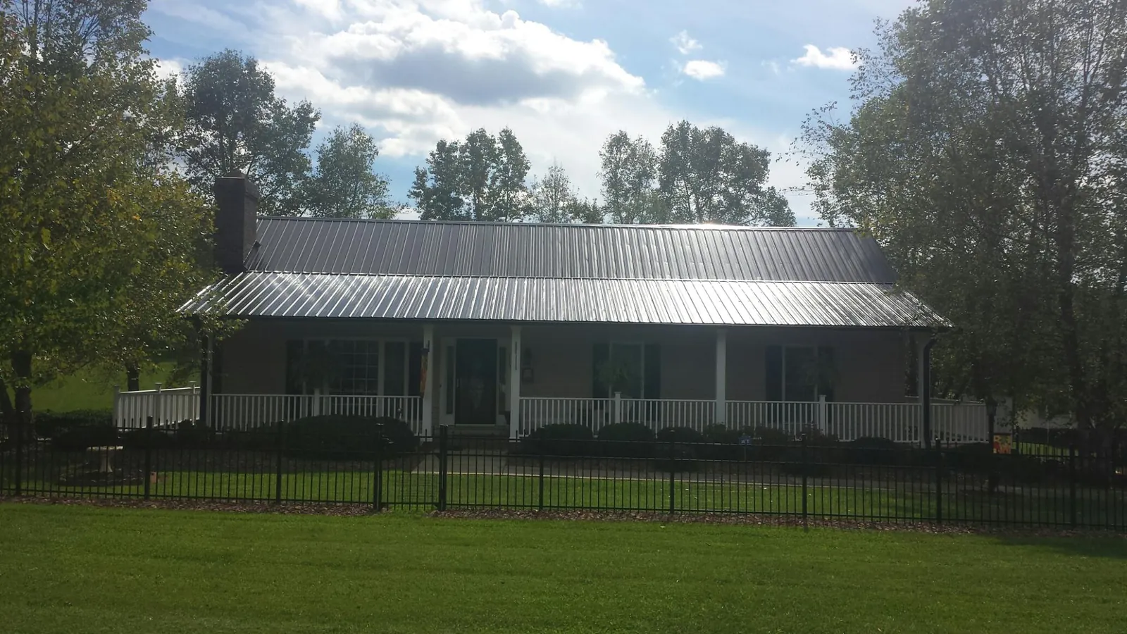 Gray metal roof on a brick ranch with a full width front porch — Gutter Guard Installation work by our crew in Central Square