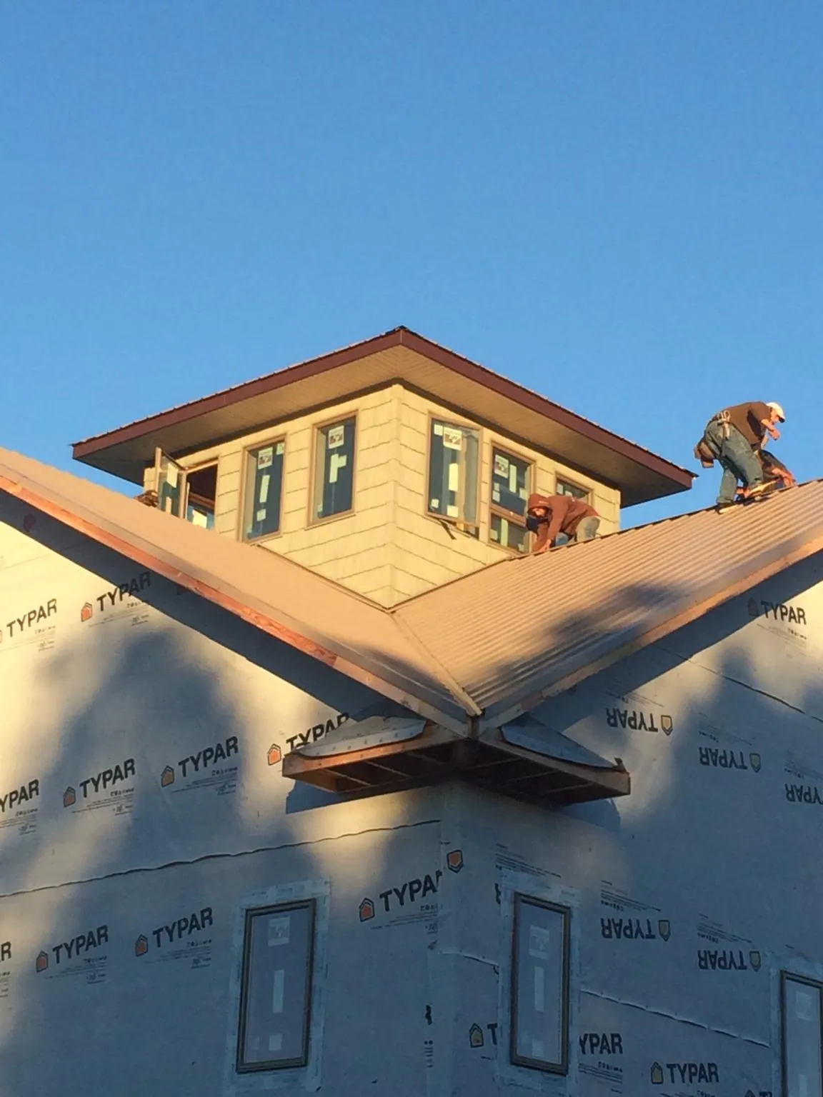 Roofers working around a rooftop cupola on a new metal roof at sunset — Roof Waterproofing in Central Square by Roofing Brothers